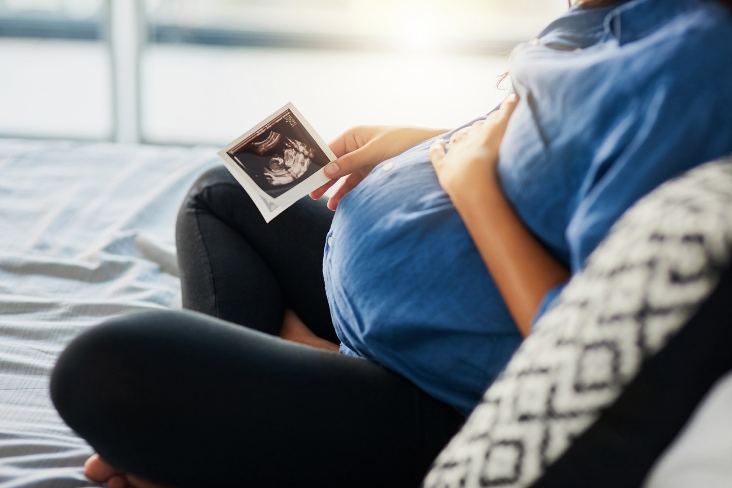 Pregnant woman sitting and holding stomach, wondering if her yeast infection will effect her baby